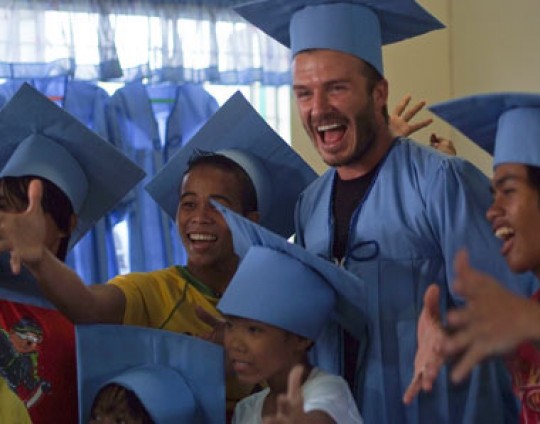 2 December 2011, Manila, Philippines - UNICEF Goodwill Ambassador David Beckham tries on a graduation gown sewn by children in a UNICEF supported centre for children who once lived and worked on the streets. Sewing classes are part of the livelihood programmes in the centre, teaching skills as well as providing clothes for the children. ©UNICEF/2011/Villafranca