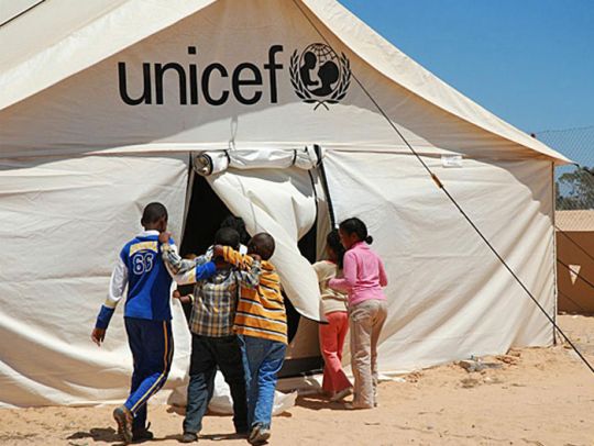 Children enter a UNICEF-supported tent school at the Shousha transit camp on the Libyan border