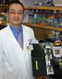 Huang with a device used to coax nerve cells to grow by stretching them