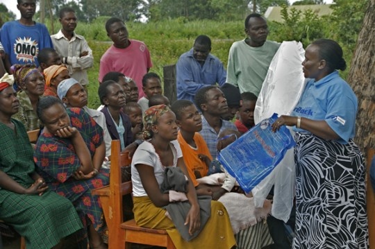 A volunteer in 2008 shows people from the Lurambi District in Western Kenya how to use incecticide-treated bednets to prevent the spread of malaria during the Integrated Prevention Demonstration Campaign sponsored by Vestergaard Frandsen. Photo by Georgina Goodwin courtesy Vestergaard Frandsen