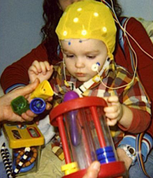 A 2-year-old in the study sits on his mother's lap while researchers measure his brain responses to words. Photo courtesy of the University of Washington.