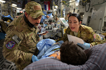 U.S. Air Force Capt. Mario Ramirez, left, and Capt. Suzanne Morris confirm a patient’s identity and prepare to administer a blood transfusion during a medical evacuation flight out of Bagram Airfield, Afghanistan. Image: DoD photo/Senior Airman Chris Willis, U.S. Air Force.